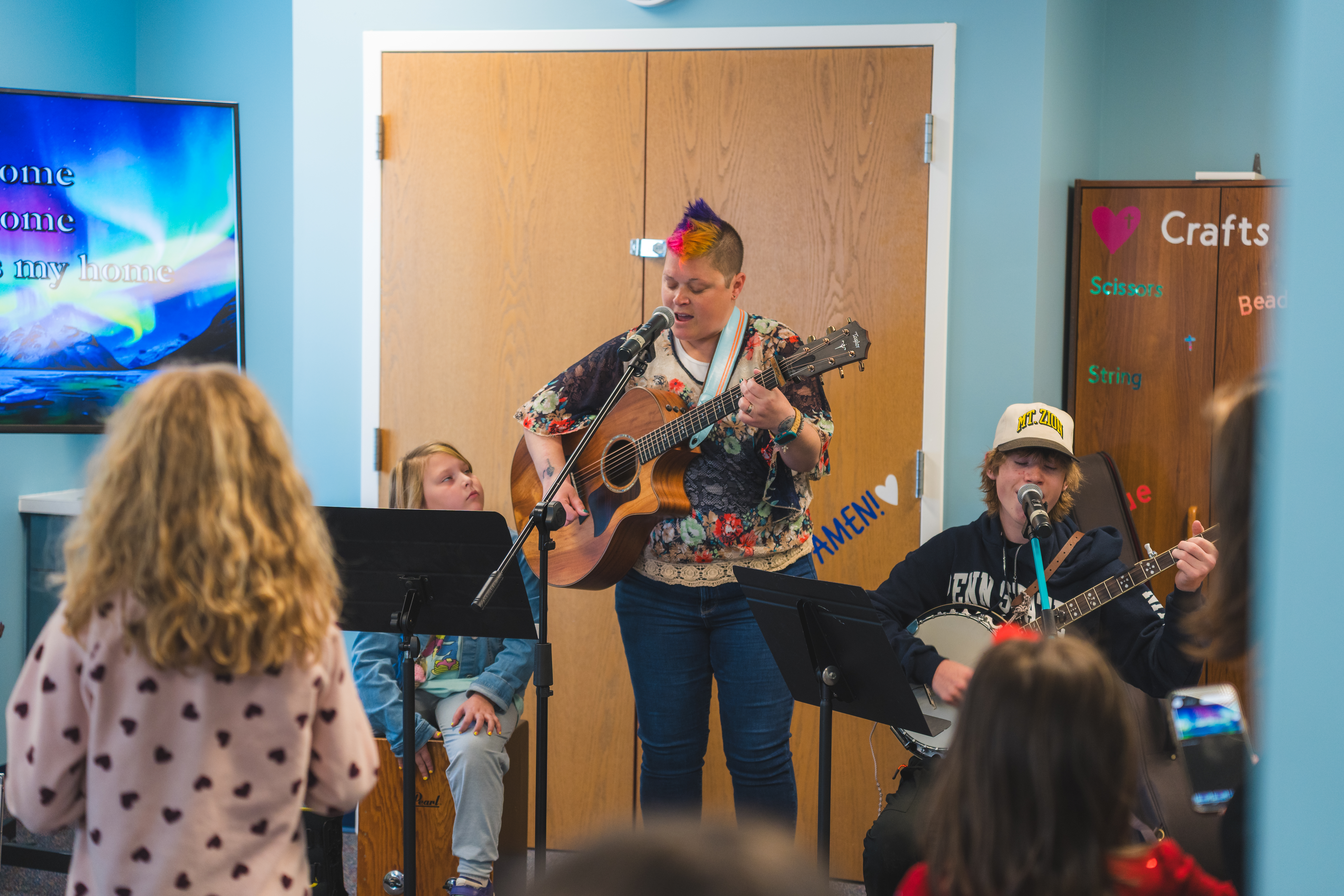 Youth leader and two youth students playing a song during kid's ministry