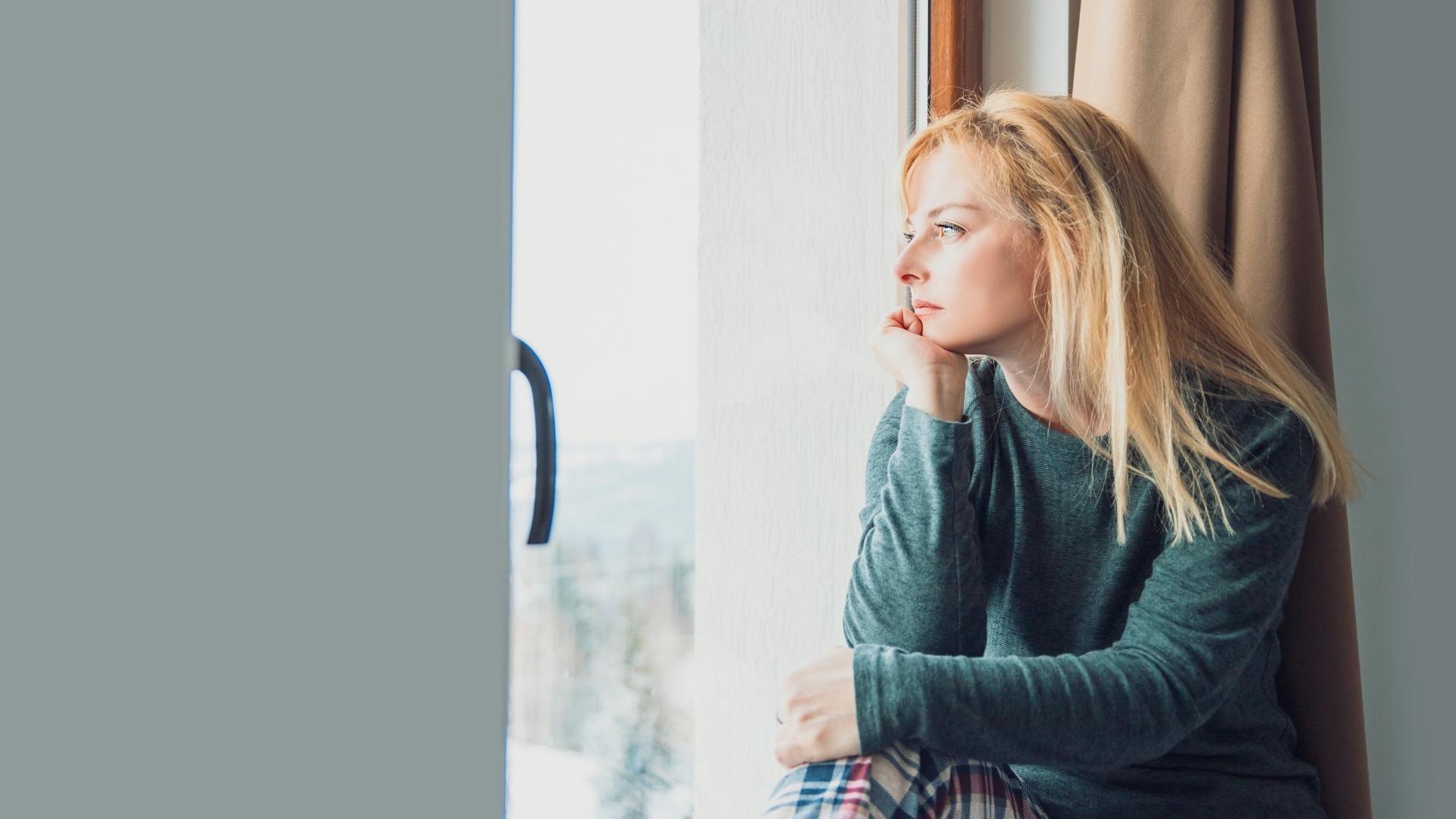 Person feeling far from God looking out window