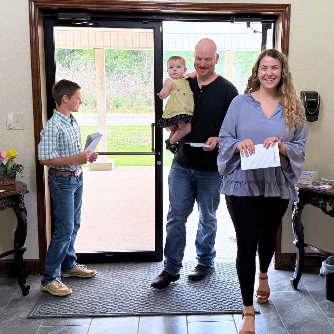 A greeter handing a bulletin to a visitor at Faith Bible Church in Lake Charles