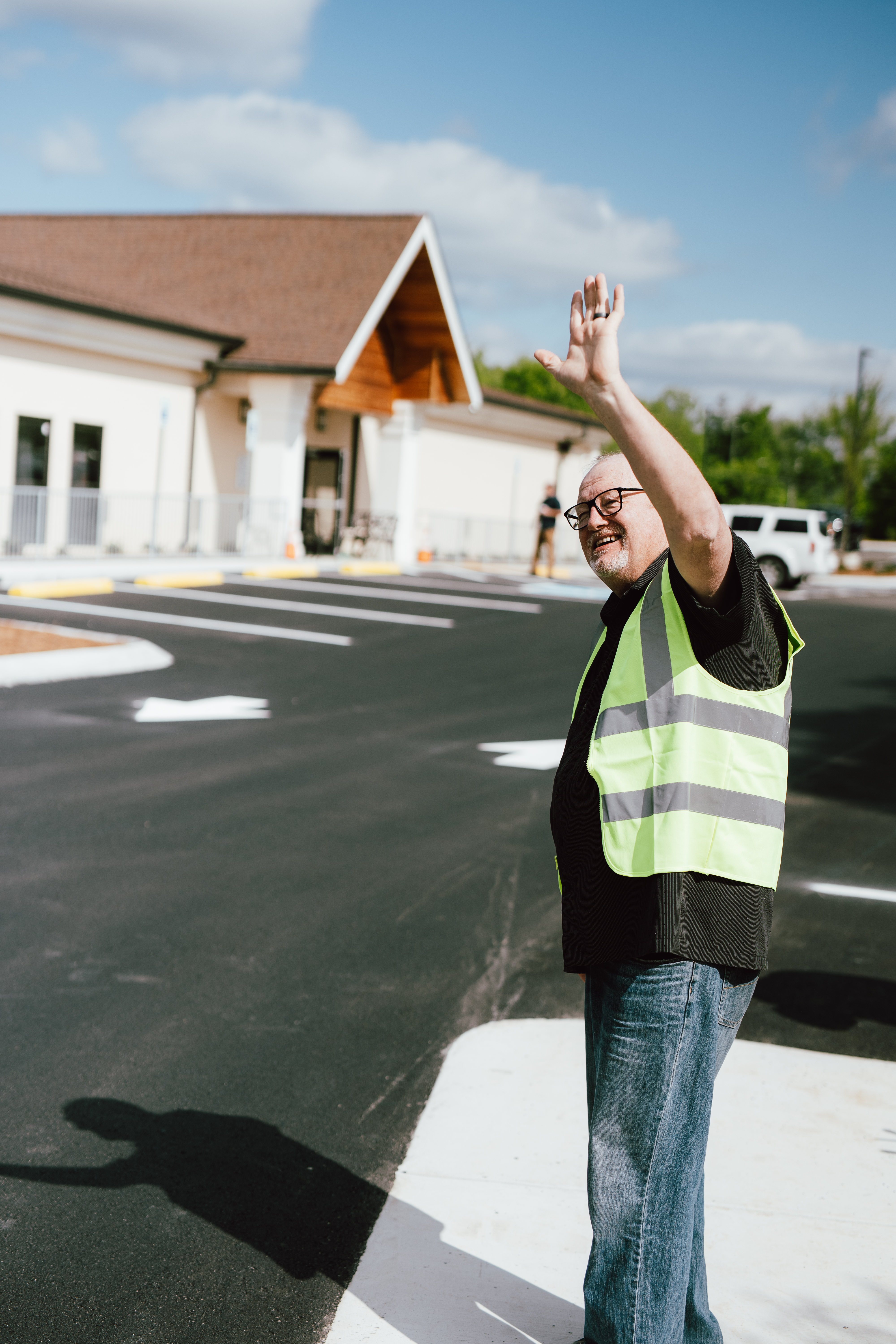 Oasis Church volunteer smiling and waving to arriving guests in Hendersonville, Tennessee.