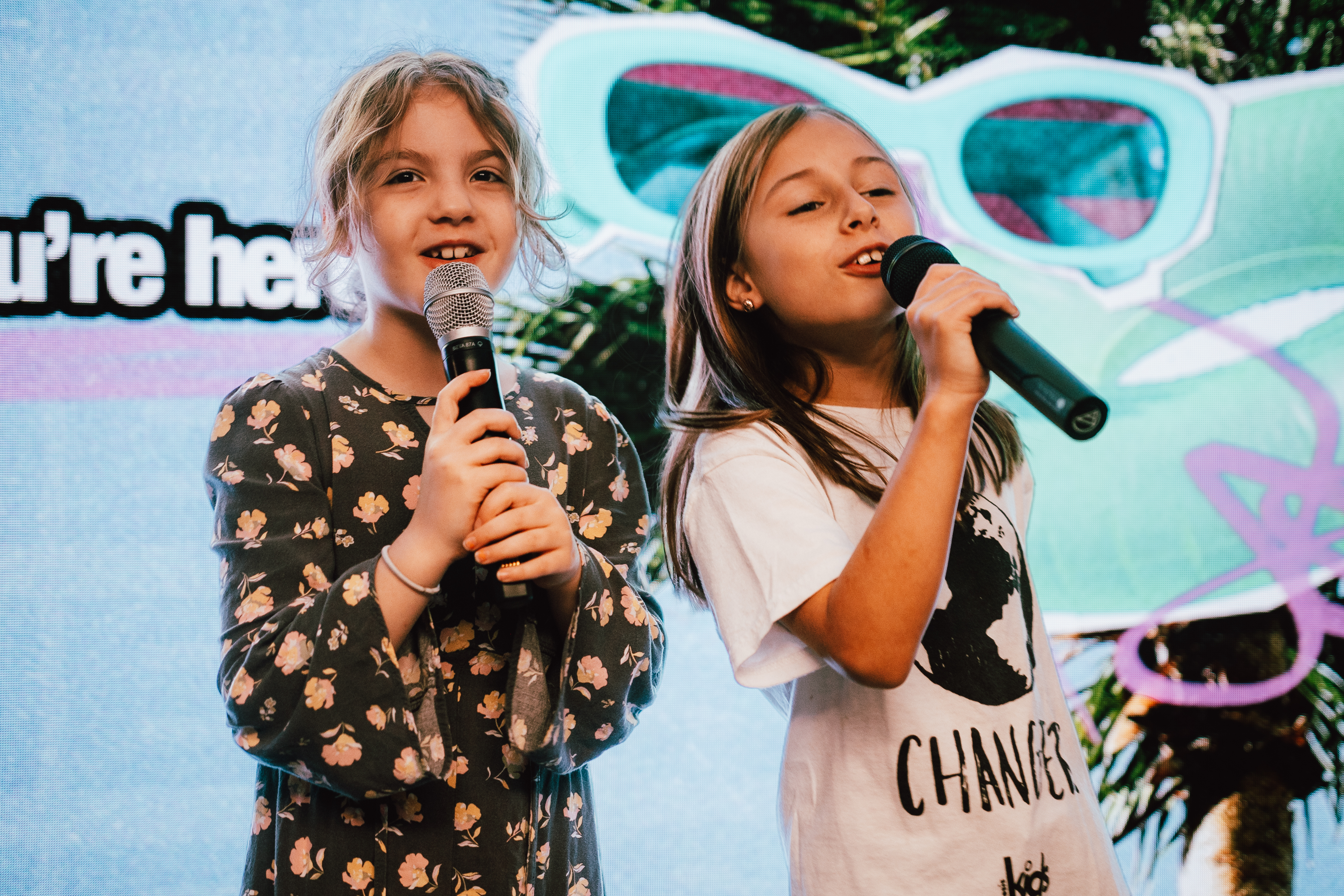 Two girls singing into microphones during an Oasis Kids gathering.