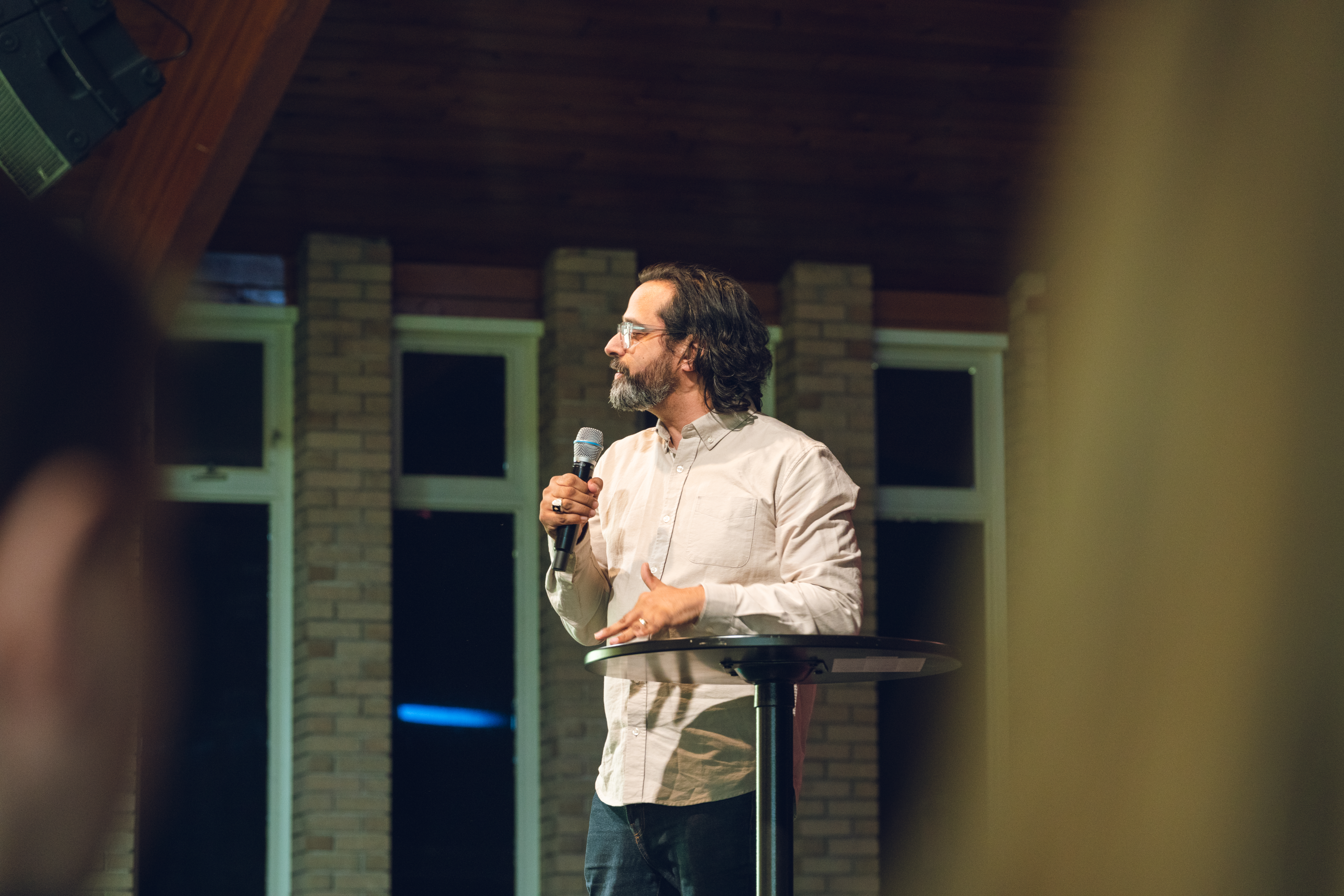 Rev. Pal Khosla delivering a message at Faith Summit St, standing on stage with a microphone and addressing the congregation.