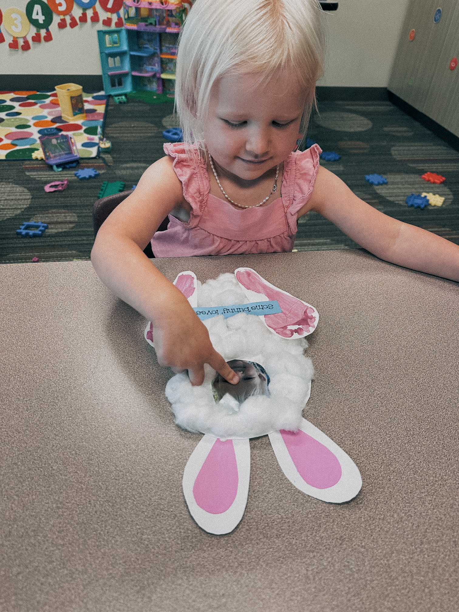 Smiling young girl creating an Easter bunny craft.