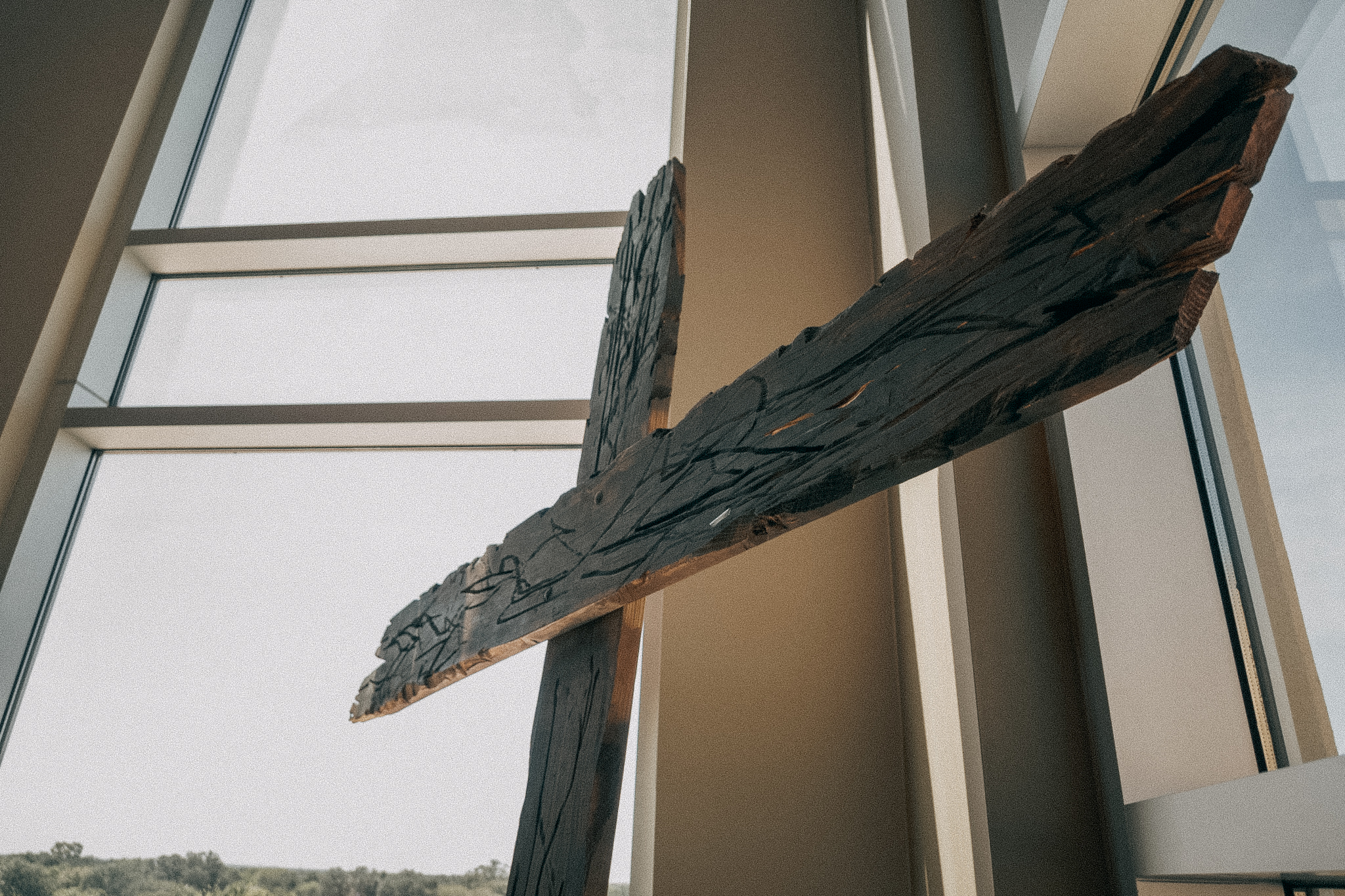 Large wooden cross displayed in the church Atrium with sky in the background.