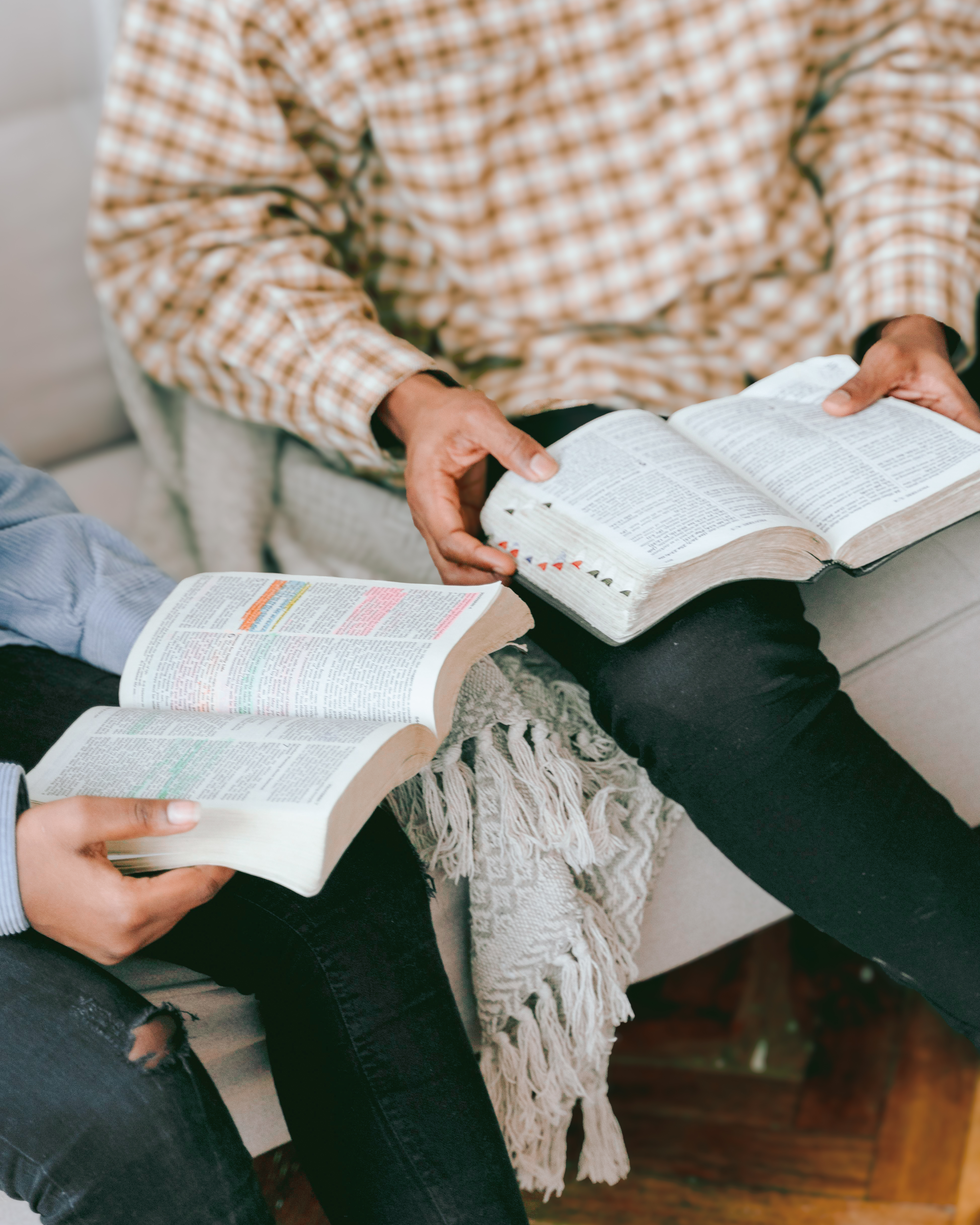 Two people opening Bibles while sitting beside each other at a small group.