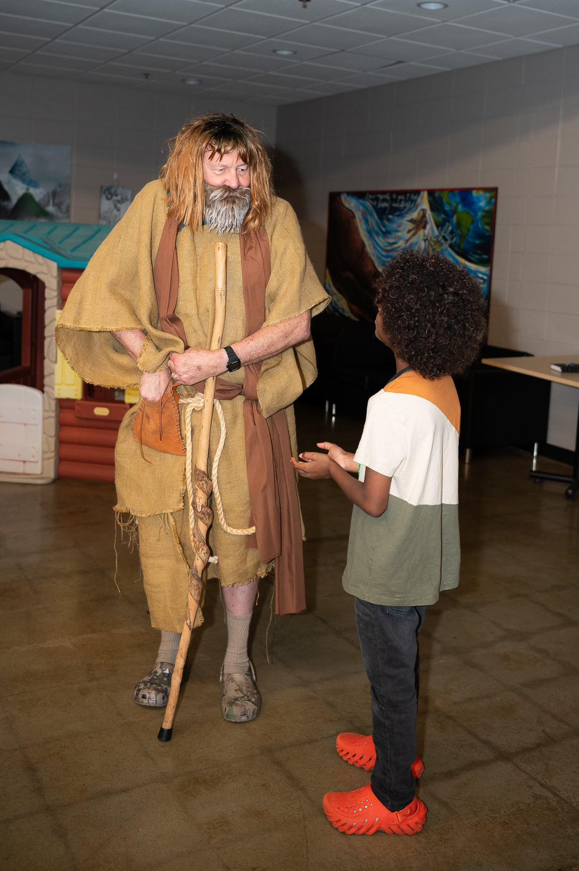 Man dressed as John the baptist talks to a child