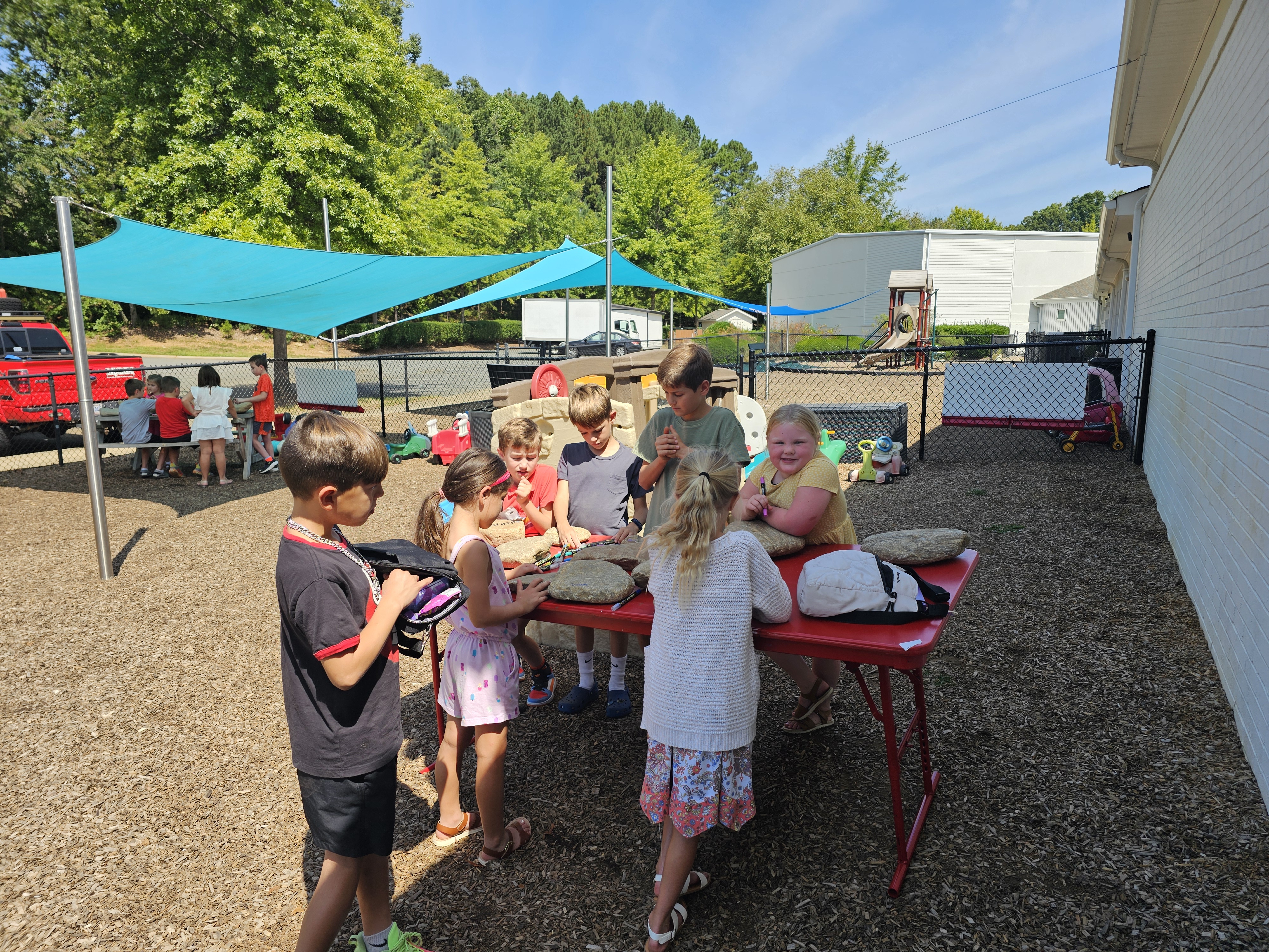 A group of kids outside helping with a service project on the table.